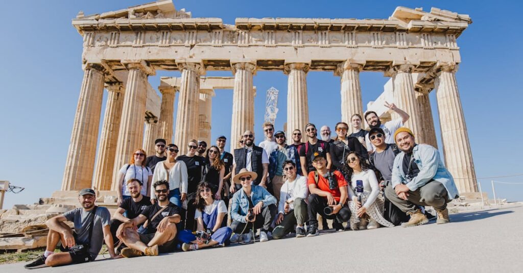 A group photo of tourists in front of the Parthenon, Athens, Greece under a clear blue sky.