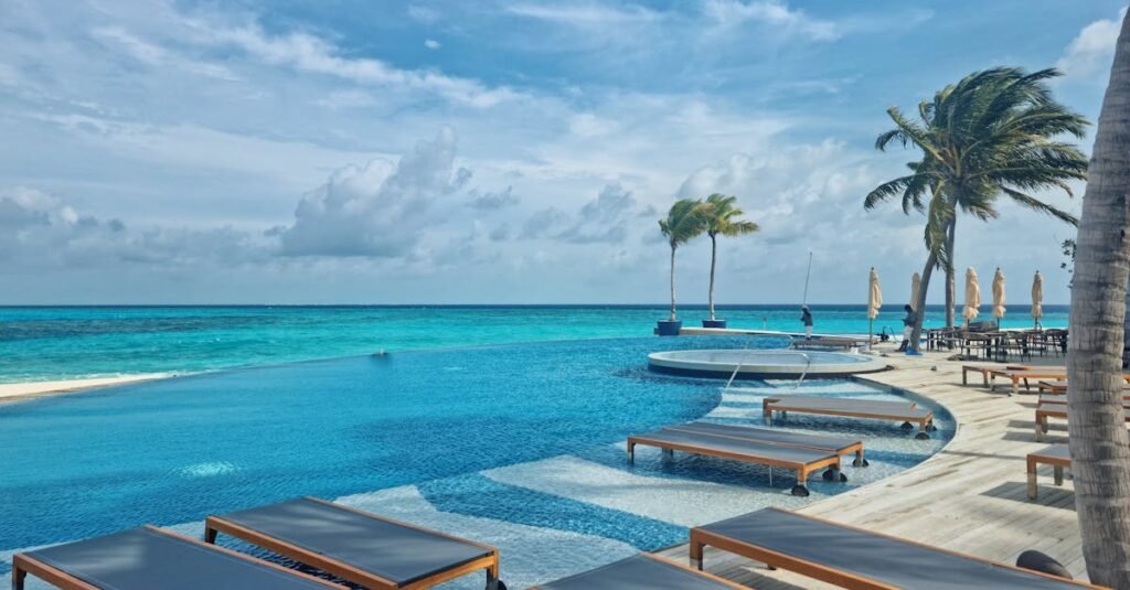 Relax by the stunning infinity pool at a luxury resort in the Maldives, surrounded by turquoise waters and palm trees.