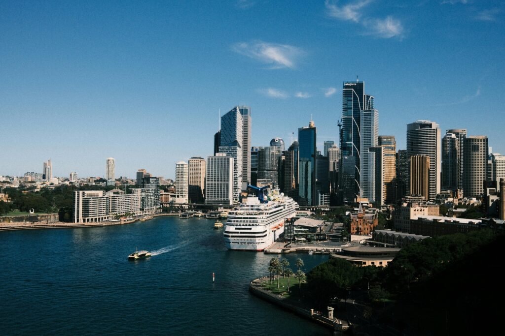 Aerial view of Sydney skyline with a cruise ship docked at the harbor under a clear blue sky.